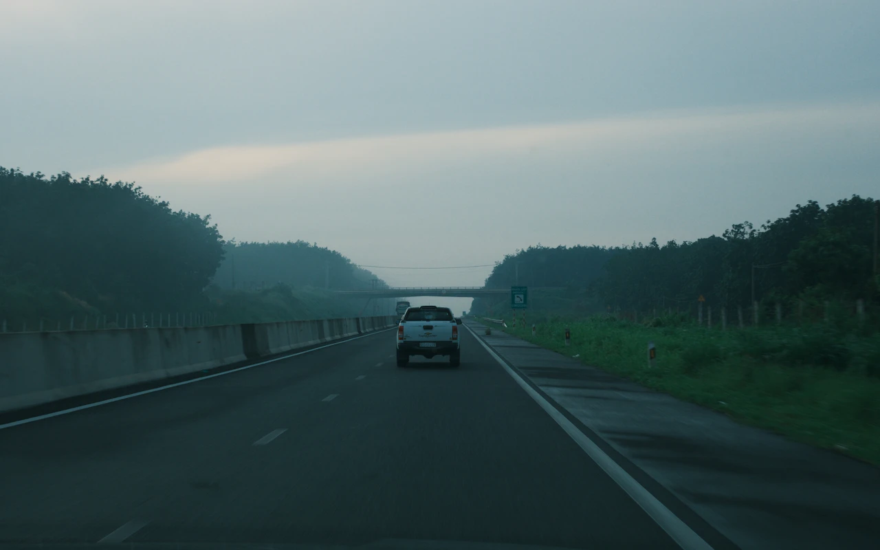 Vehicles on a highway beneath an overcast sky.